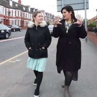 Two staff walking down a road in Crumpsall discussing health issues.