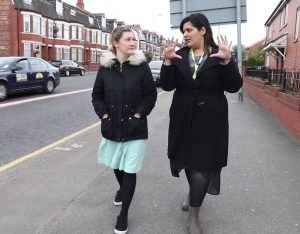 Two staff walking down a road in Crumpsall discussing health issues.